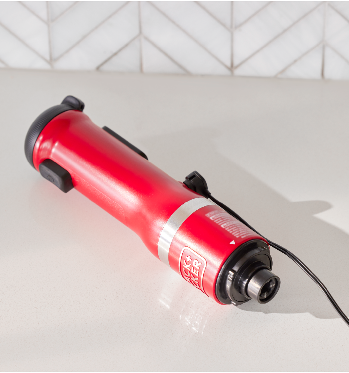 Birdseye view of the red, BLACK+DECKER kitchen wand power unit lying on it's side charging