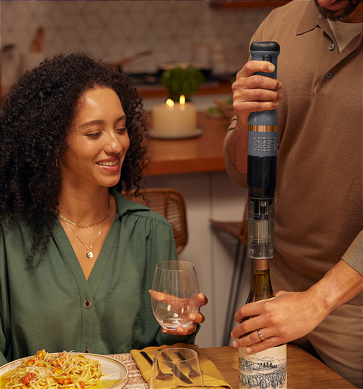 Talent using the grey, BLACK+DECKER kitchen wand wine opener to open a bottle of wine