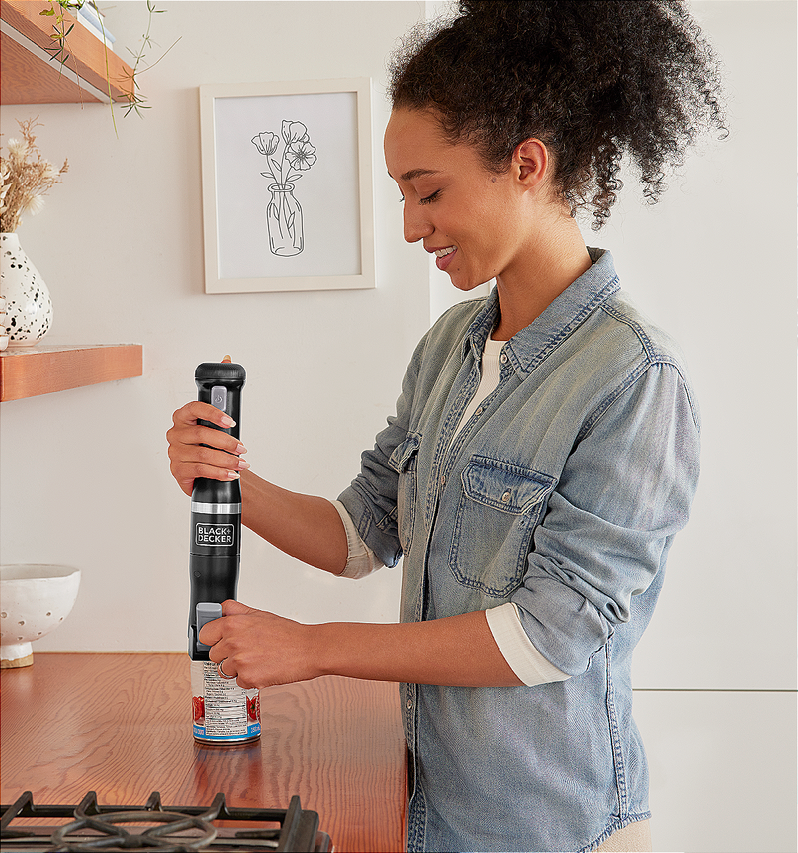 Talent using the black, BLACK+DECKER kitchen wand can opener to open canned tomatoes
