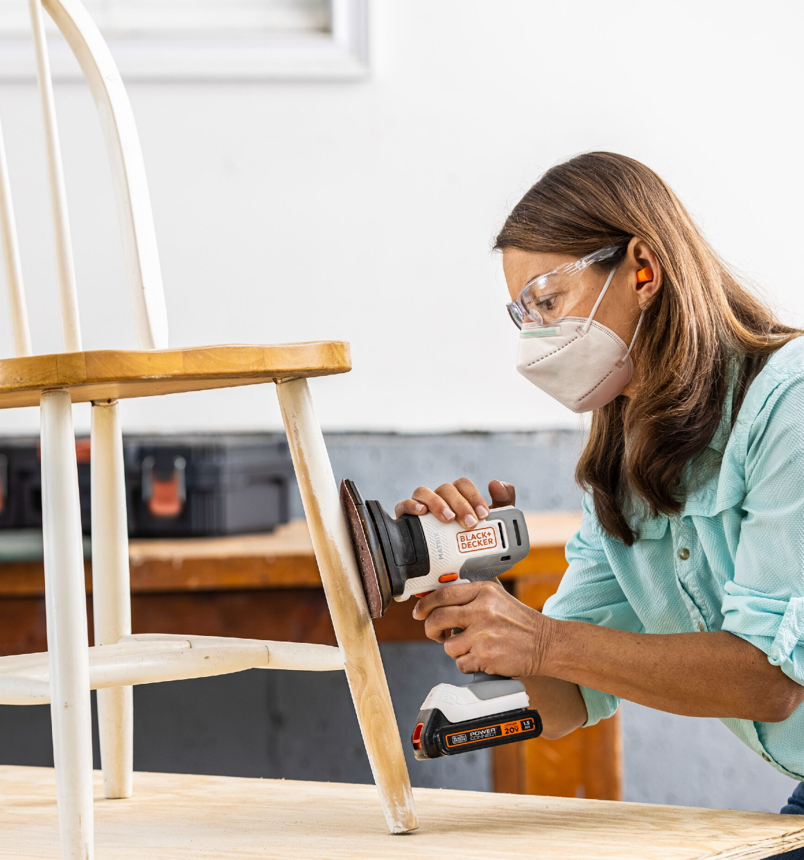 Woman using the 20V Max Matrix with sander attachment to smooth legs of a chair.