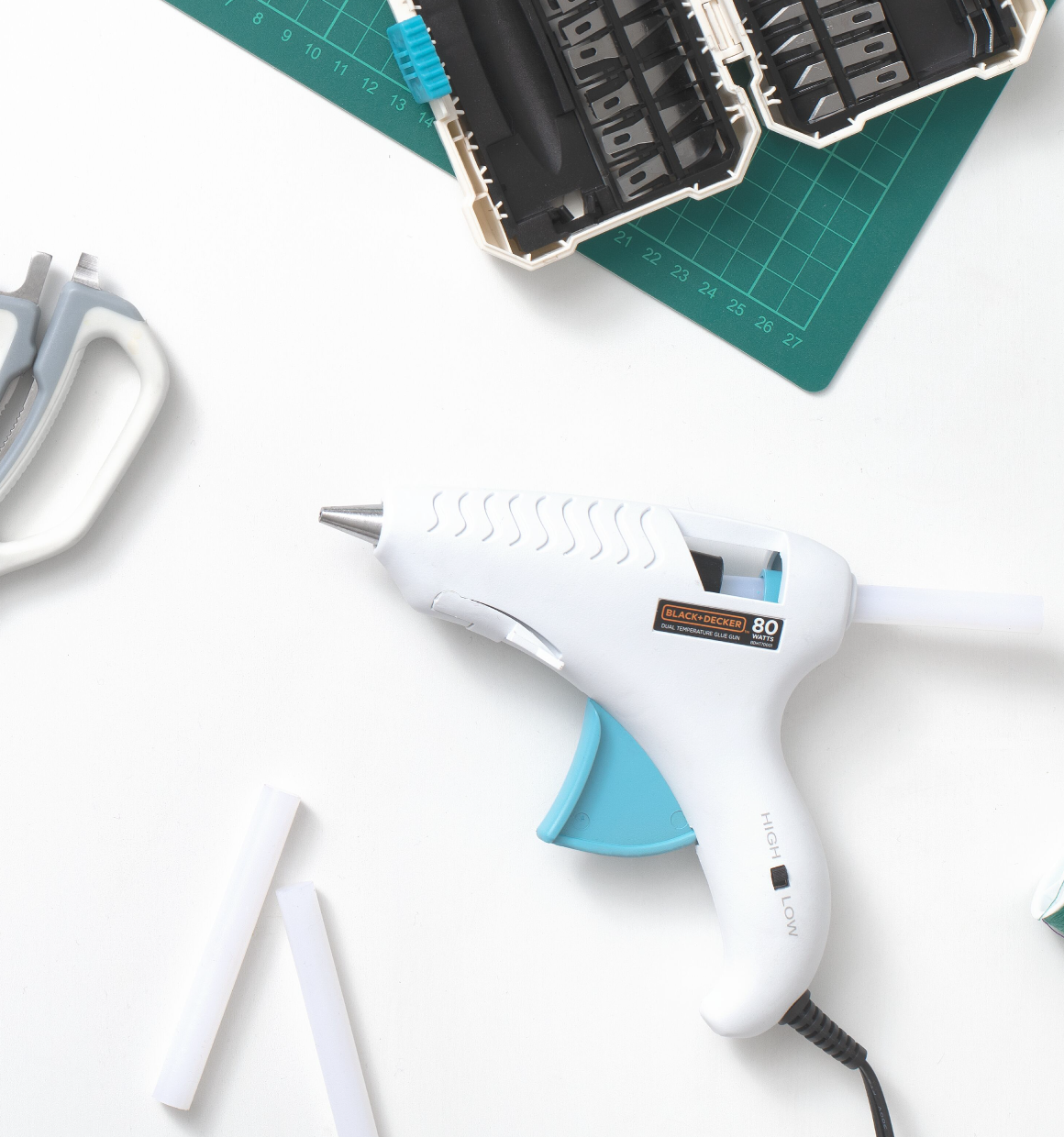 lay down image of manual crafting tools from the BLACK+DECKER Crafting Collection, including corded hot glue gun, glue sticks, crafting shears scissors and hobby knife set.