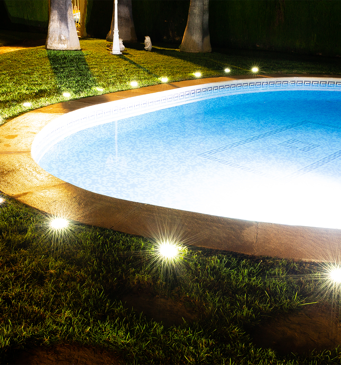 BLACK+DECKER Solar Disk Lights surrounding a pool at night time.