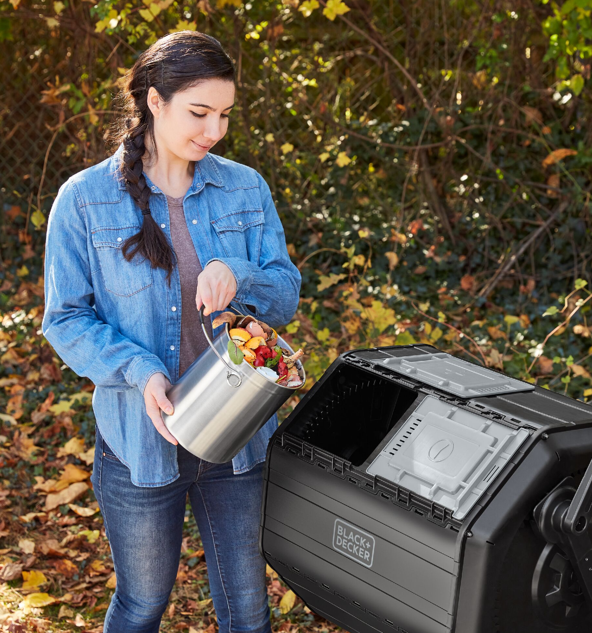 Woman dumping food scraps from the BLACK+DECKER Countertop Compost Bin into the BLACK+DECKER Tumbler Composter