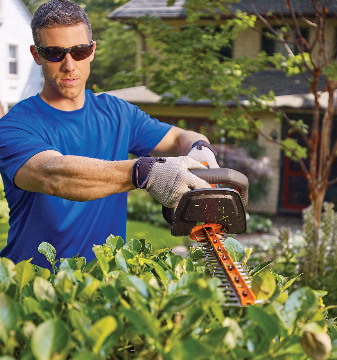 Lithium 22 inch POWER CUT Hedge Trimmer being used by person to trim bushes.