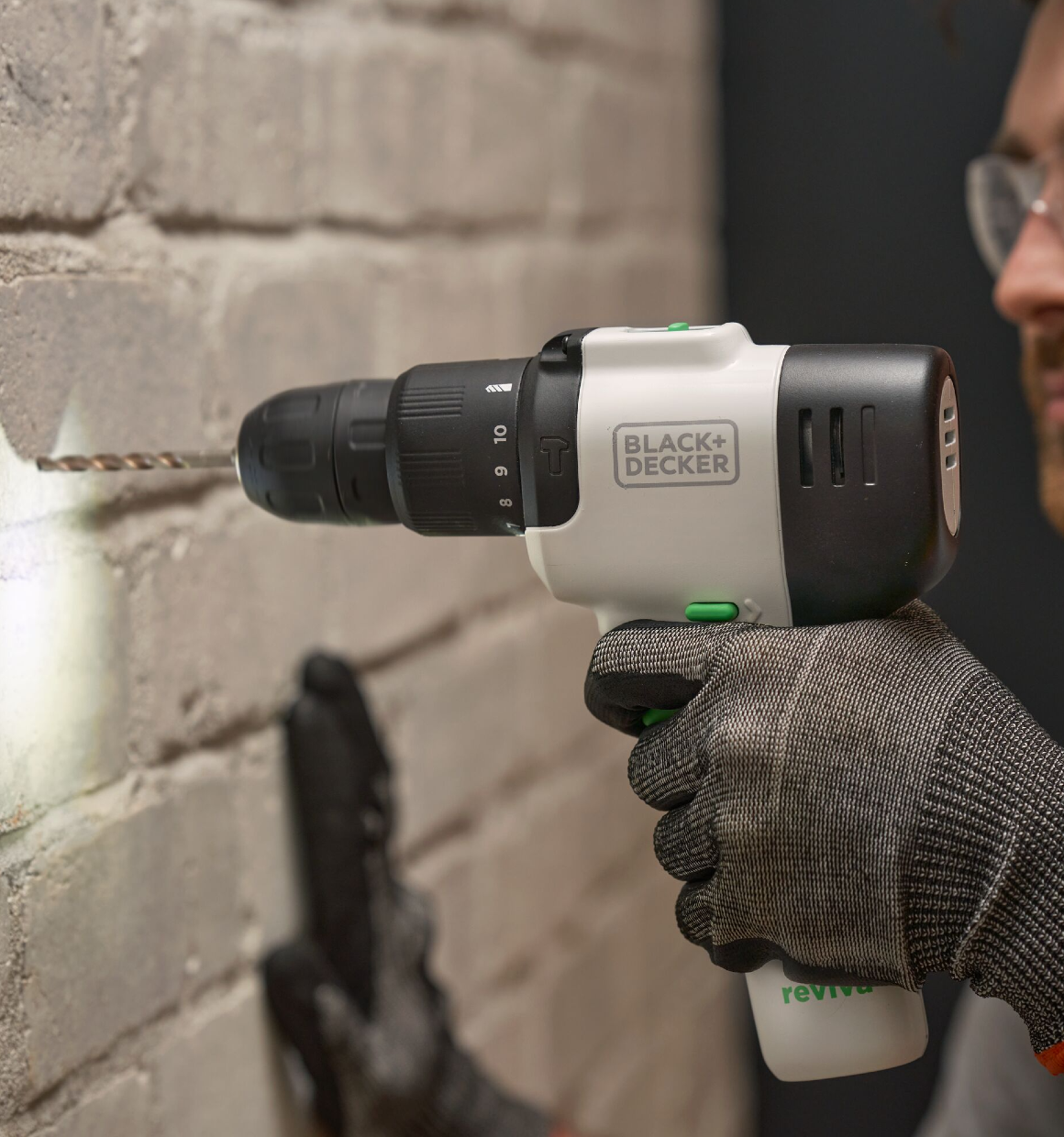 Close up of a Reviva 12V Hammer Drill drilling into brick while its LED illuminates the workspace.