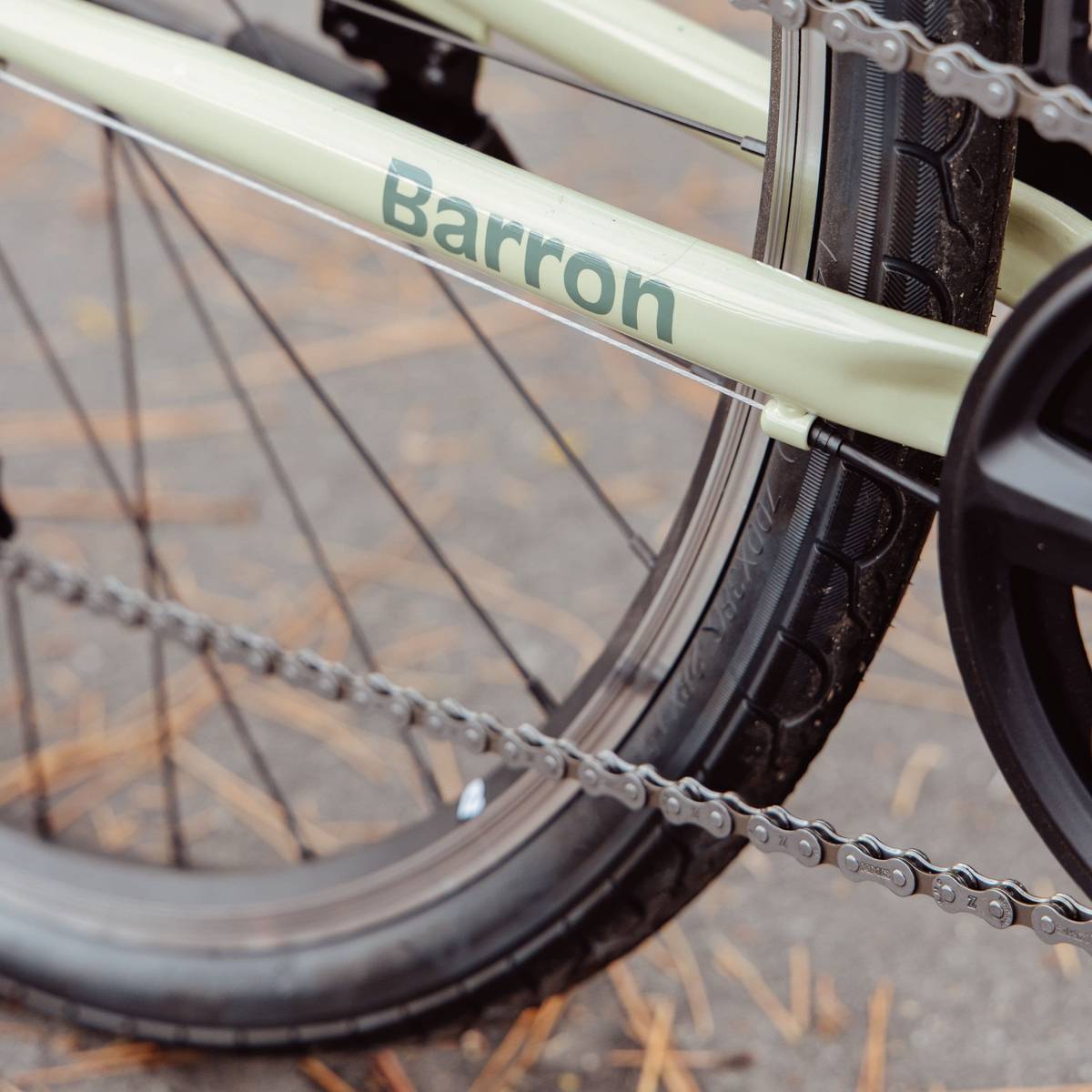 Close-up of a light green bicycle's rear wheel and frame with "Barron" on it.