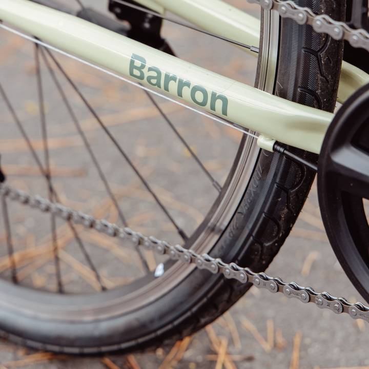 Close-up of a light green bicycle's rear wheel and frame with "Barron" on it.