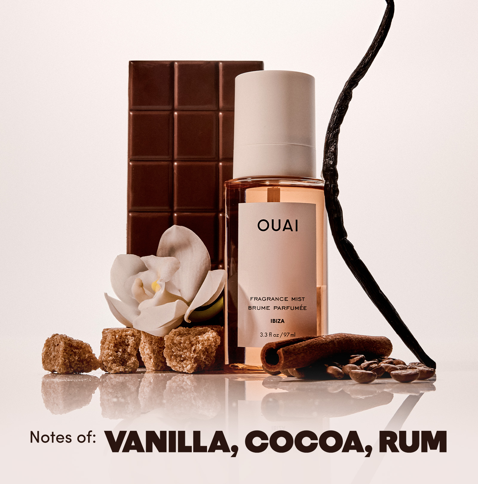 Ibiza scented hair and body fragrance mist bottle next to a vanilla bean on a white background