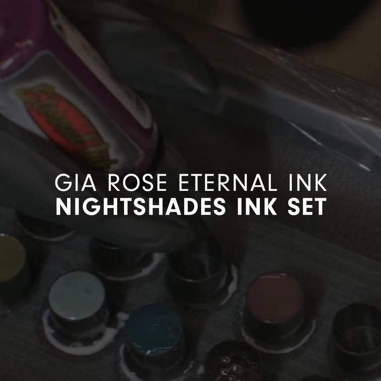 Gloved hand holding a bottle of Gia Rose Eternal Ink near ink pots.