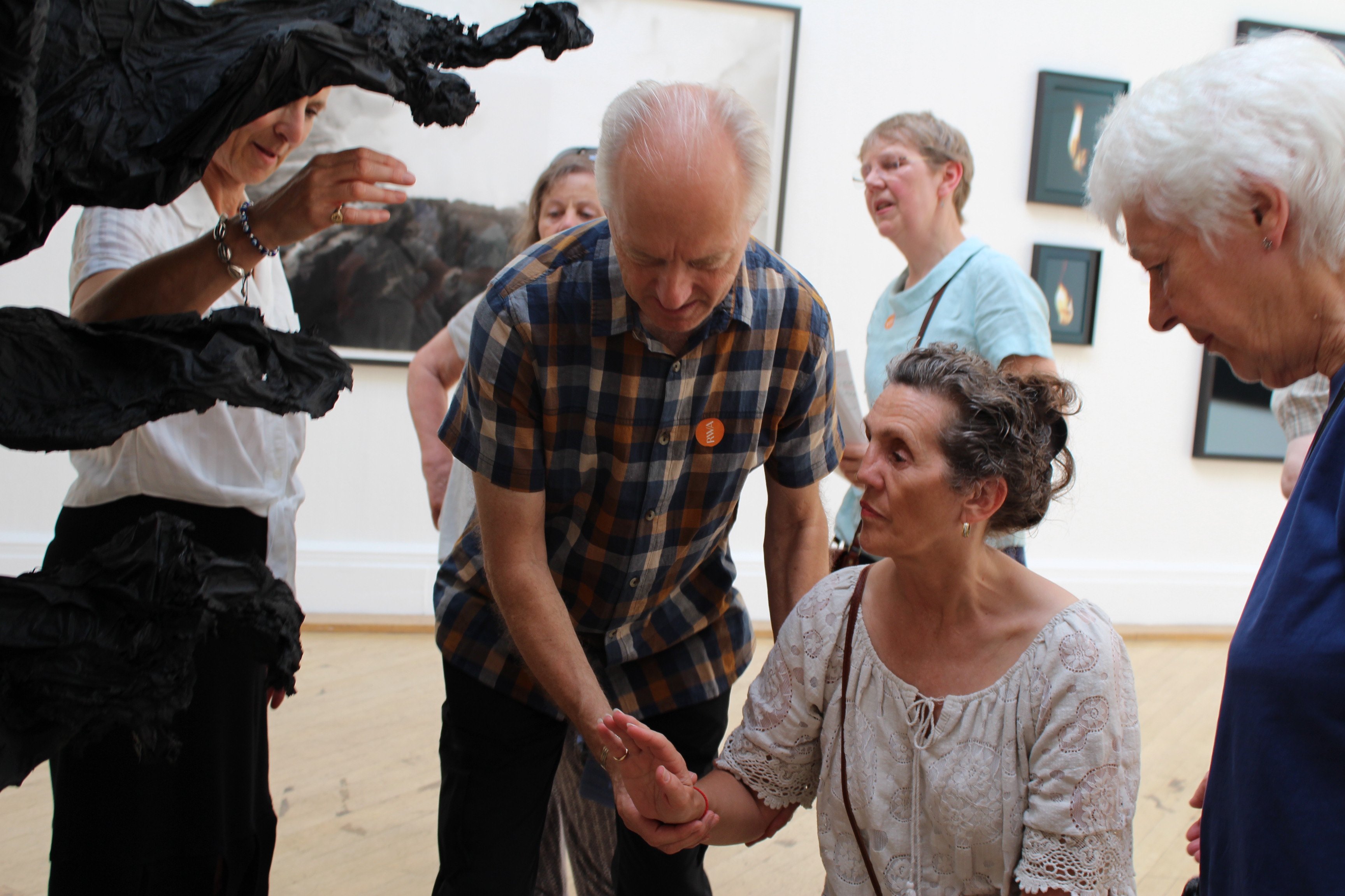 An image of a woman's hand being guided towards a sculpture 