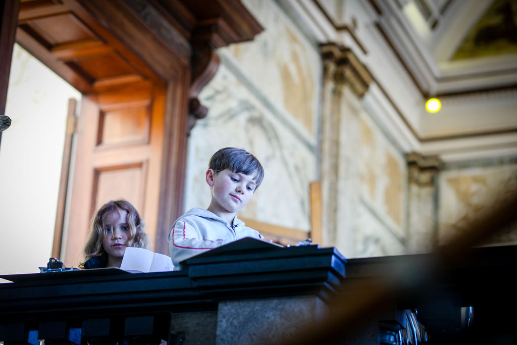 An image of two children with the interior marble of the RWA behind them 