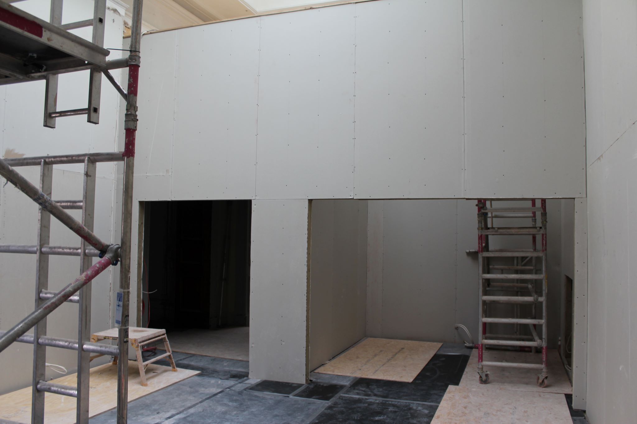 Internal space with scaffolding to the near left side and wall dividers at the back of the room 