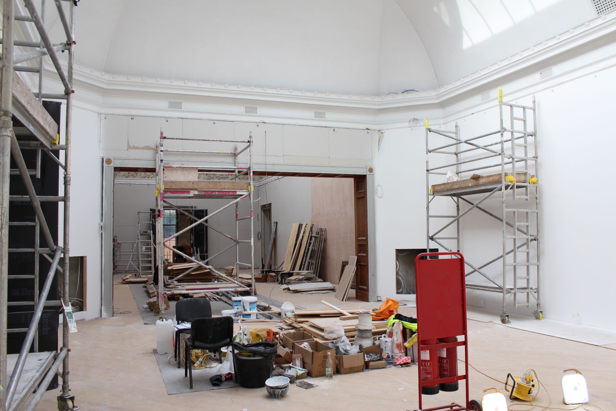 A gallery space with scaffolding and building materials in the centre of the room 