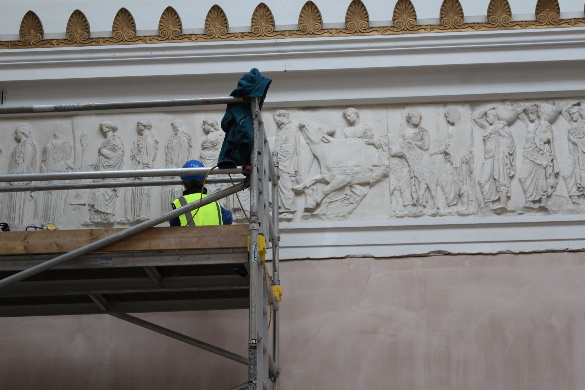 A person in a high vis jacket is on scaffolding working on the RWA gallery decorative walls 