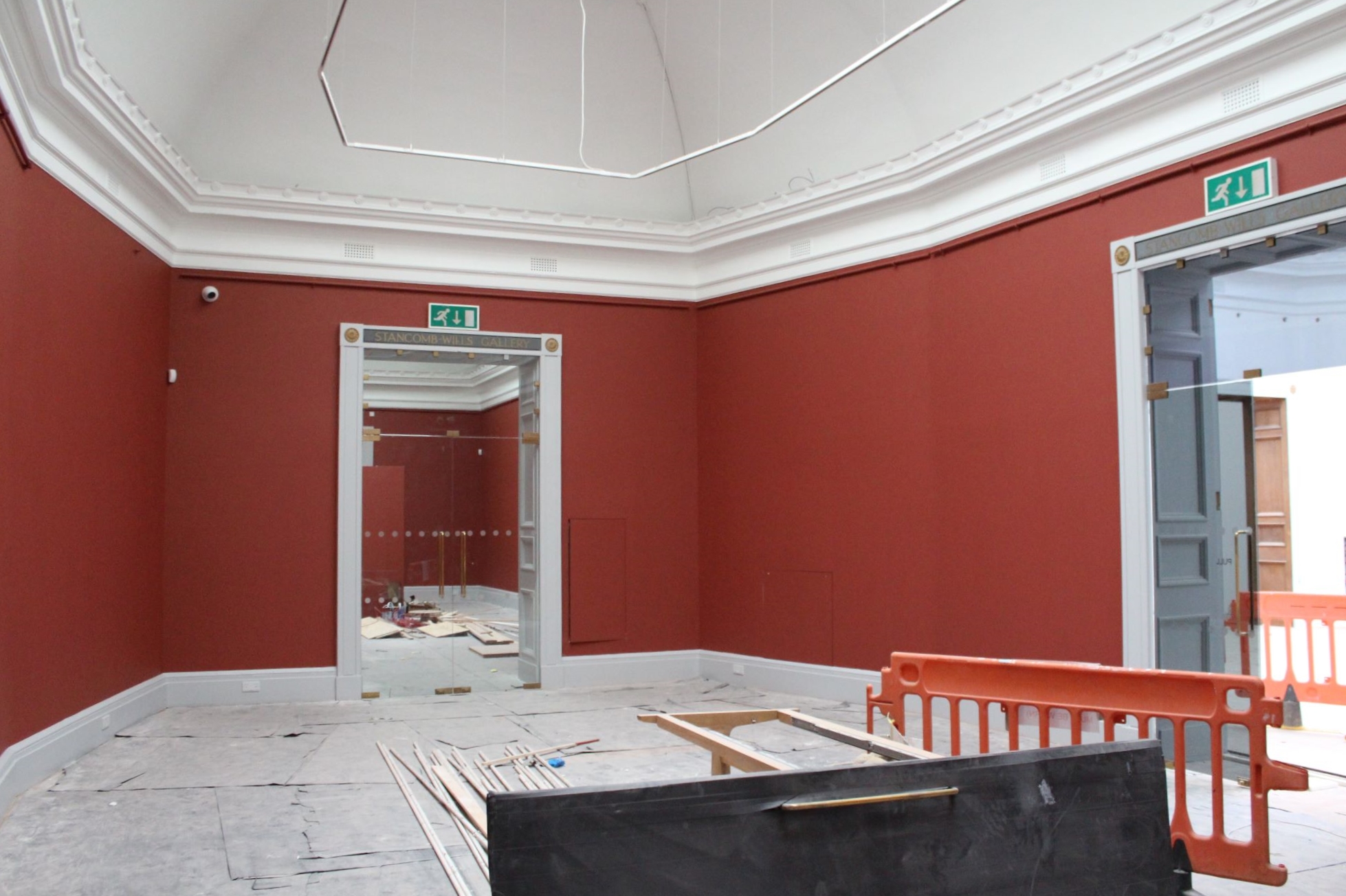 A large gallery space with red painted walls and white ceiling 