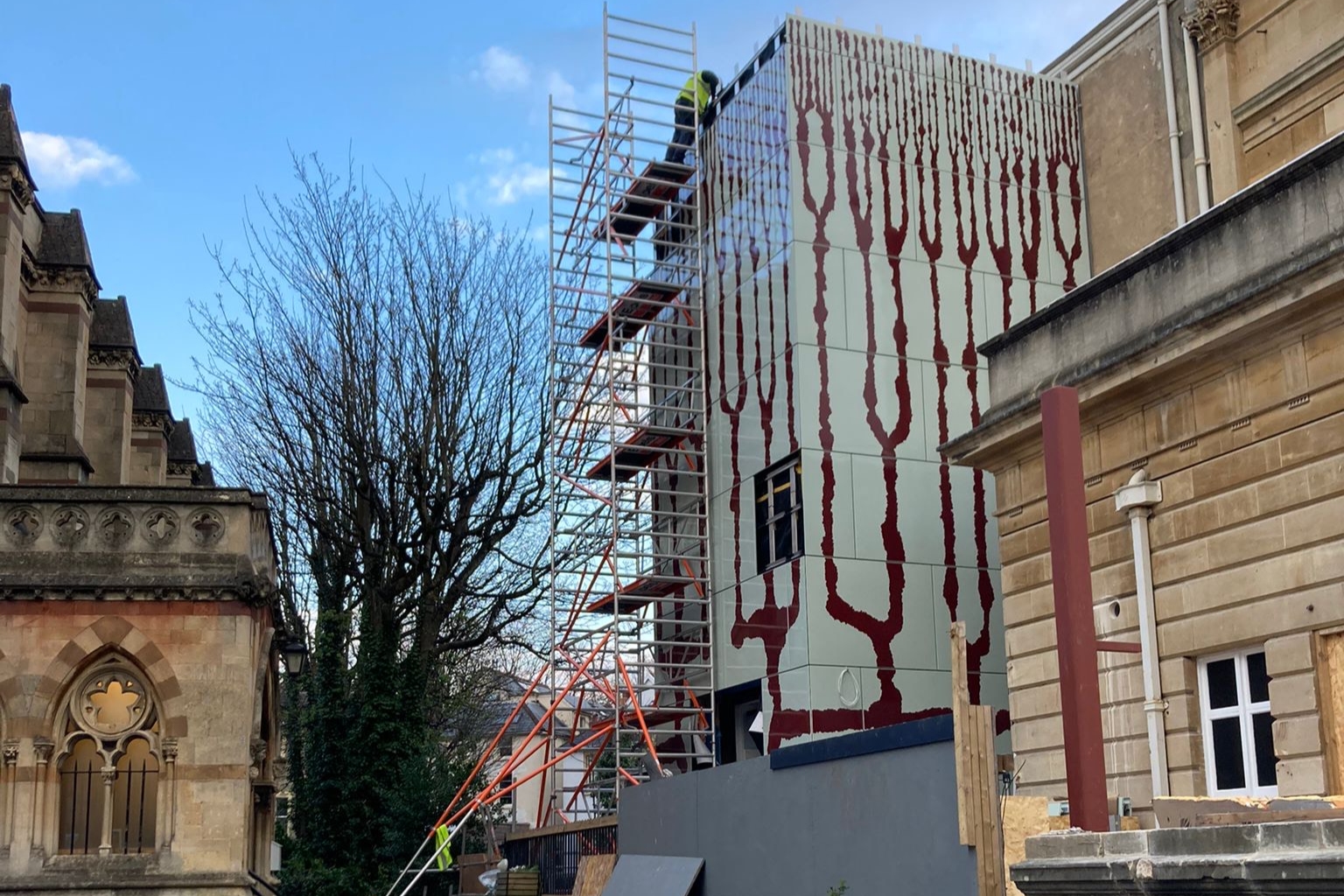 Scaffolding surrounds the new RWA lift structure, enamel panels are being installed with blue sky in the background 