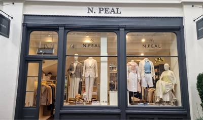 N.Peal Covent Garden storefront with large display windows showcasing mannequins dressed in elegant neutral and pastel-toned outfits, with the store interior visible behind them