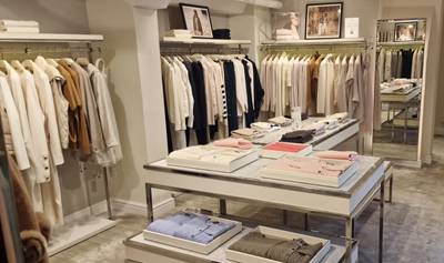 N.Peal Covent Garden store interior with racks of neatly hung garments in neutral tones and folded knitwear displayed on layered tables in the centre