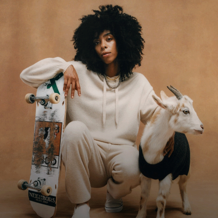 Skater wearing The Essential Cashmere Hoodie and Sweatpants with goat wearing the Cashmere Holiday Dog Sweater