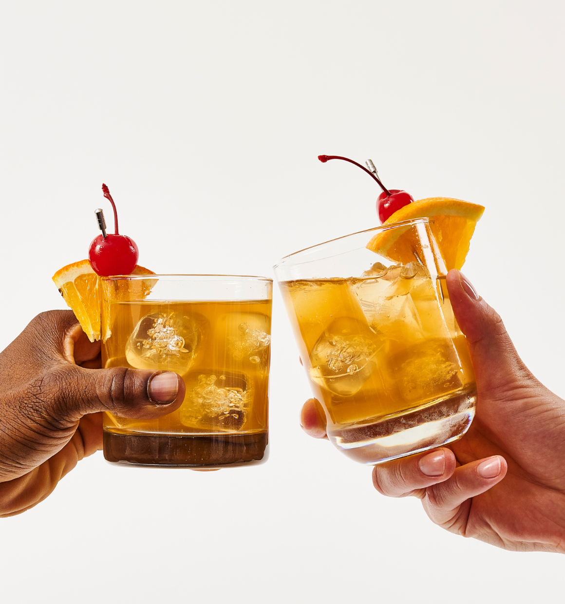 two hands cheersing with old fashioned cocktails