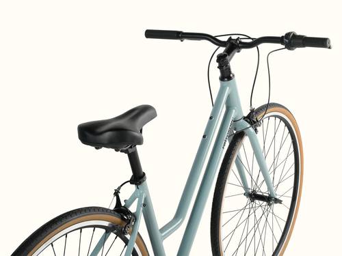 A close-up of a light blue Harper Plus 7-Speed bicycle with black handlebars and seat, isolated on a white background.