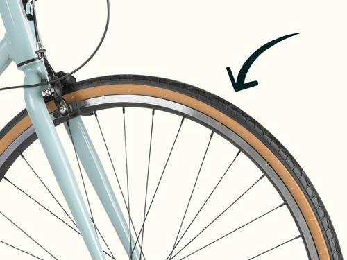 Front wheel of a light blue Harper Plus 7-Speed bicycle with a black arrow pointing to the tire tread.