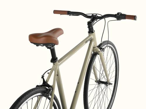 A close-up of a beige Harper Plus 7-Speed city bicycle with a brown saddle and handles against a white background.