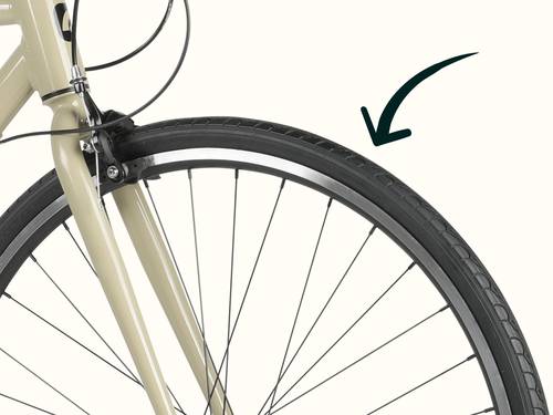 Close-up of a bicycle front wheel with a brake pad and black arrow pointing to the tire tread.