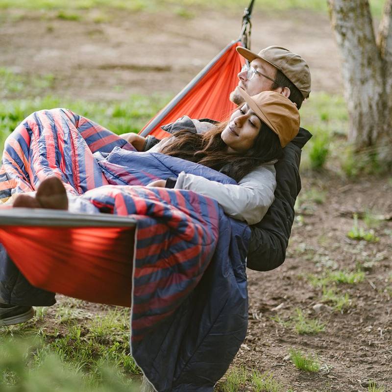 A couple snuggling on a hammock with a Rumpl 2 person blanket
