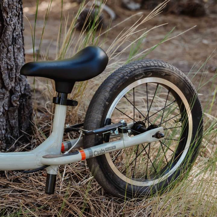 A Cub Plus XL 14" Kids' Balance Bike featuring a seat and a tire mounted on its frame, positioned against a neutral background.