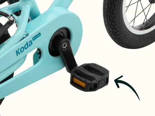 Close-up of the Robins Egg Blue Koda Plus 12" Kids' Bike pedal and part of the wheel with the brand "Koda Plus" visible and a drawn arrow pointing to the pedal.