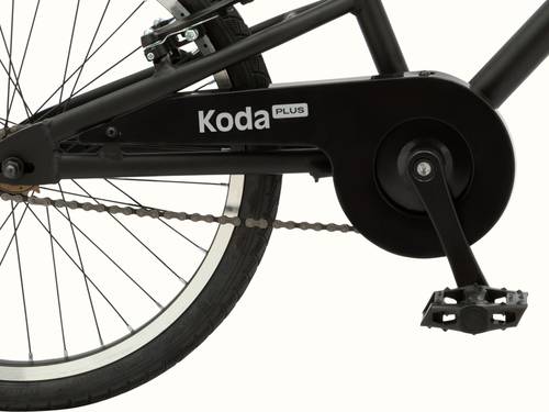 Close-up of the Koda Plus 20" Kids' bicycle's black rear wheel, chain, and pedal with "Koda PLUS" on the chainguard.