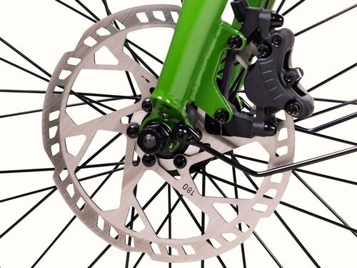 Close-up of a green bicycle fork with a disc brake rotor, caliper, and spokes, showcasing the braking system's detail.