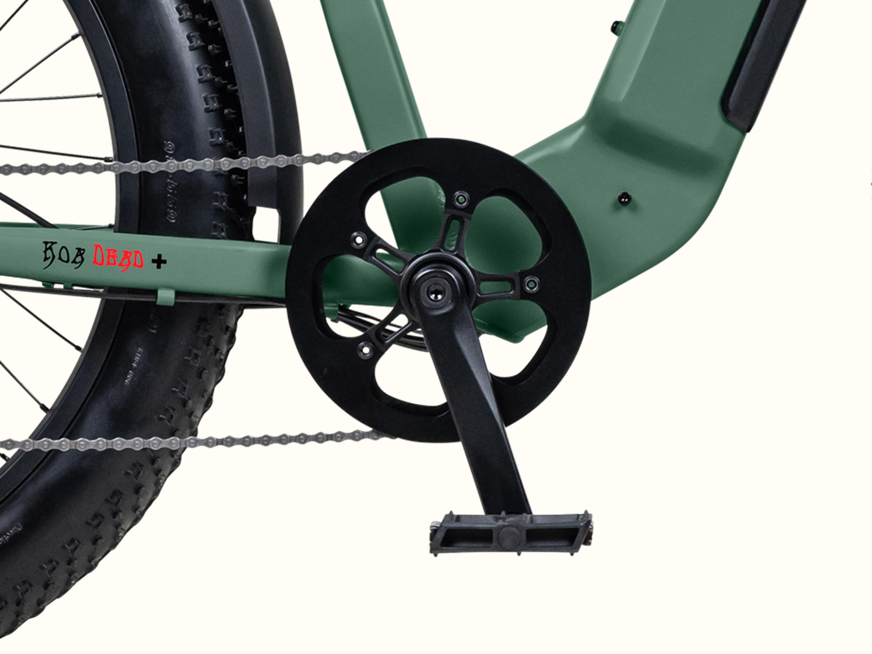 Close-up of the Grateful Dead Koa Rev+ Fat Tire Electric Bike's pedal and crank set, featuring a green frame and bold 