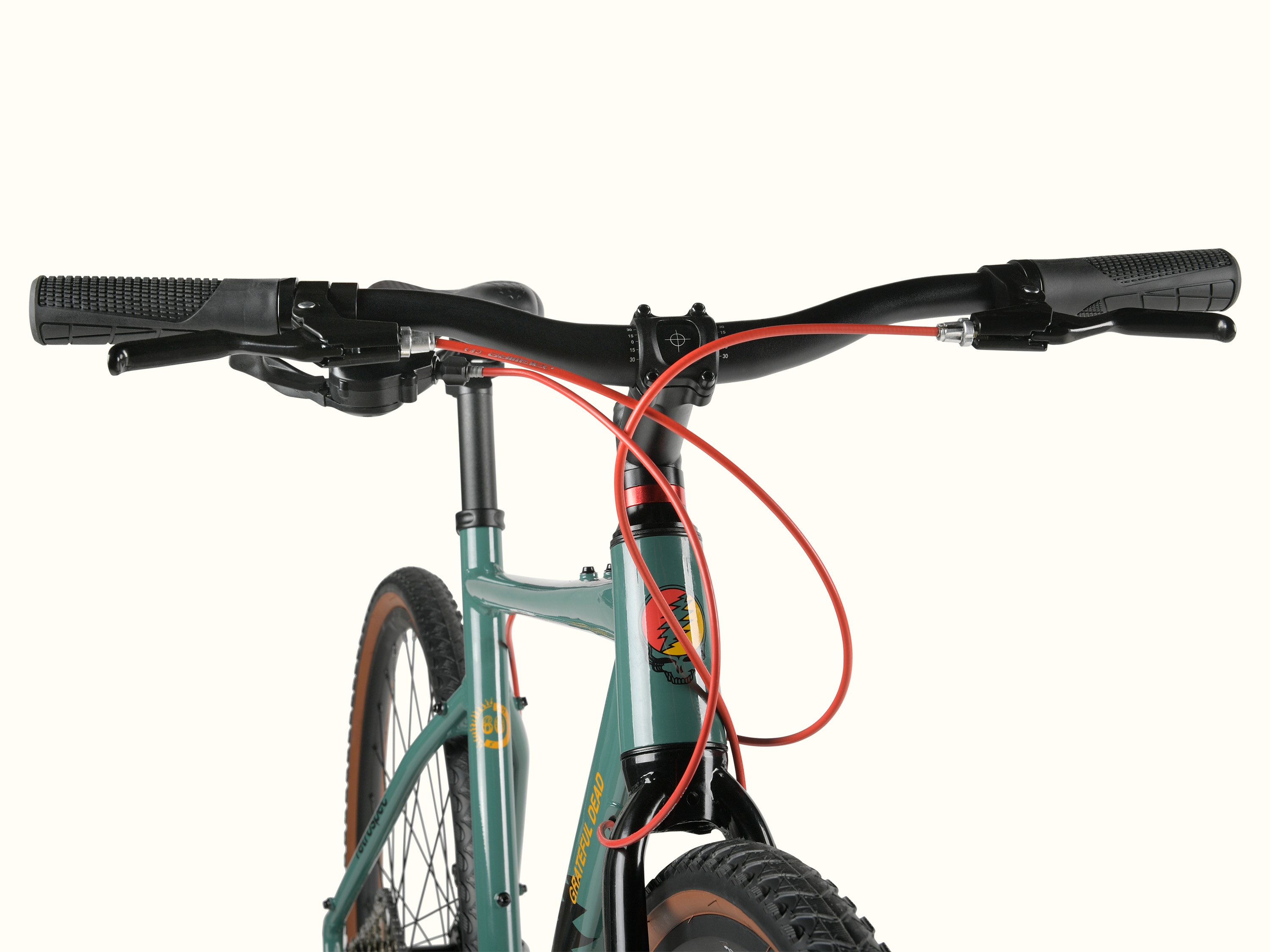 Close-up of the Grateful Dead Amok 8 Speed Step Over Gravel Adventure Bike's handlebars featuring black grips, red brake cables, and a colorful bike frame with a Grateful Dead 