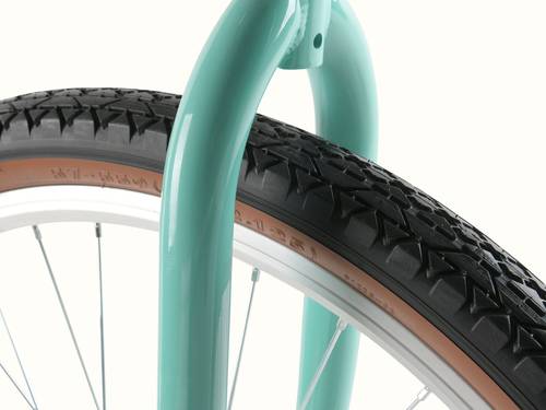 Close-up of a teal bike frame supporting a black tire with a textured tread and silver rim, highlighting the bicycle's design.