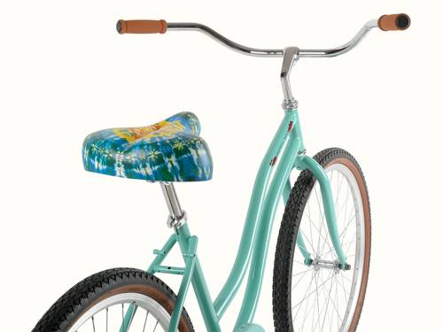 A teal bicycle with a colorful tie-dye seat and brown rubber grips, showcasing a sleek, retro design and brown wall tires.