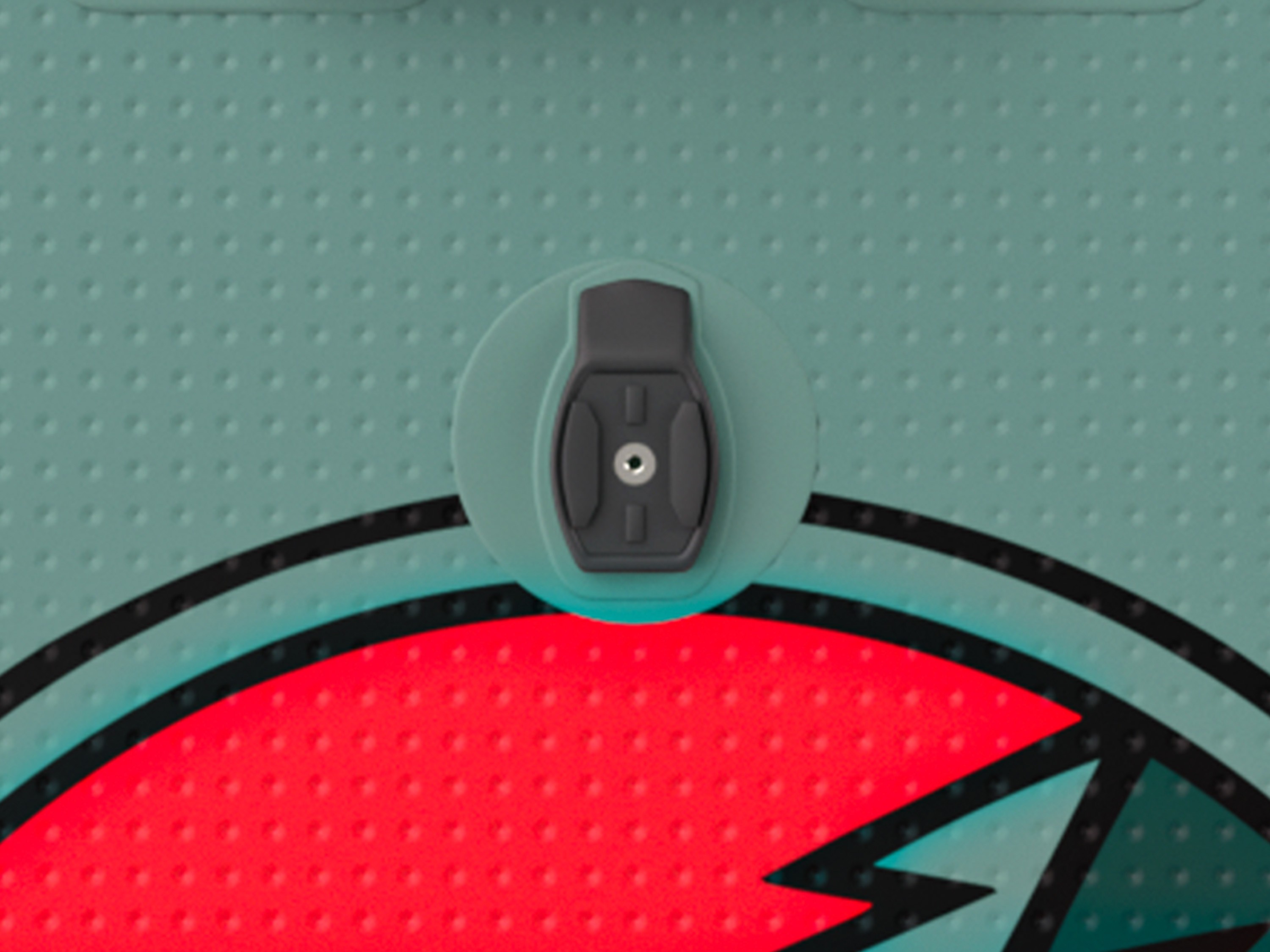 Close-up of a textured surface featuring an embedded black attachment point with a silver insert, surrounded by colorful graphics.