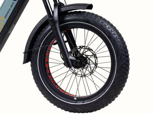 Close-up of the Grateful Dead Valen Rev+ Electric Fat Tire Bike's front wheel featuring a black tire with red accents and a disc brake, mounted on a sleek, modern frame.