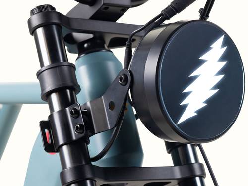 Close-up of the Grateful Dead Valen Rev+ Electric Bicycle's front light with a sleek black case and a glowing Grateful Dead lightning bolt design on it.