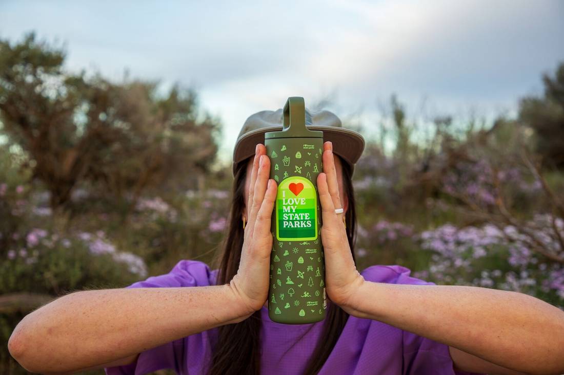 Woman holding up MiiR x Bale Breaker Wide Mouth Bottle with two hands showing printed design