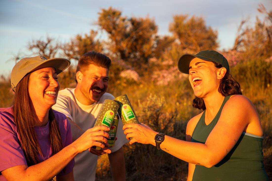 People laughing and cheer-sing with MiiR x Bale Breaker Wide Mouth Bottle in nature.