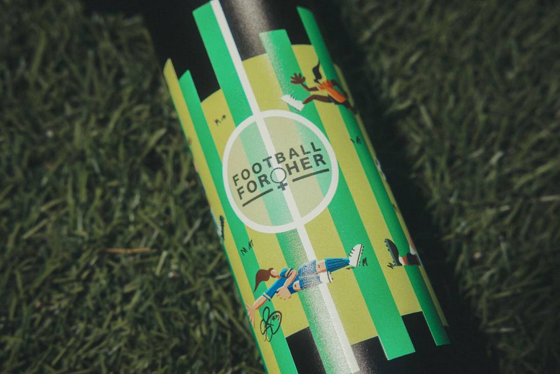 Close up of Football For Her design on bottle in grass.