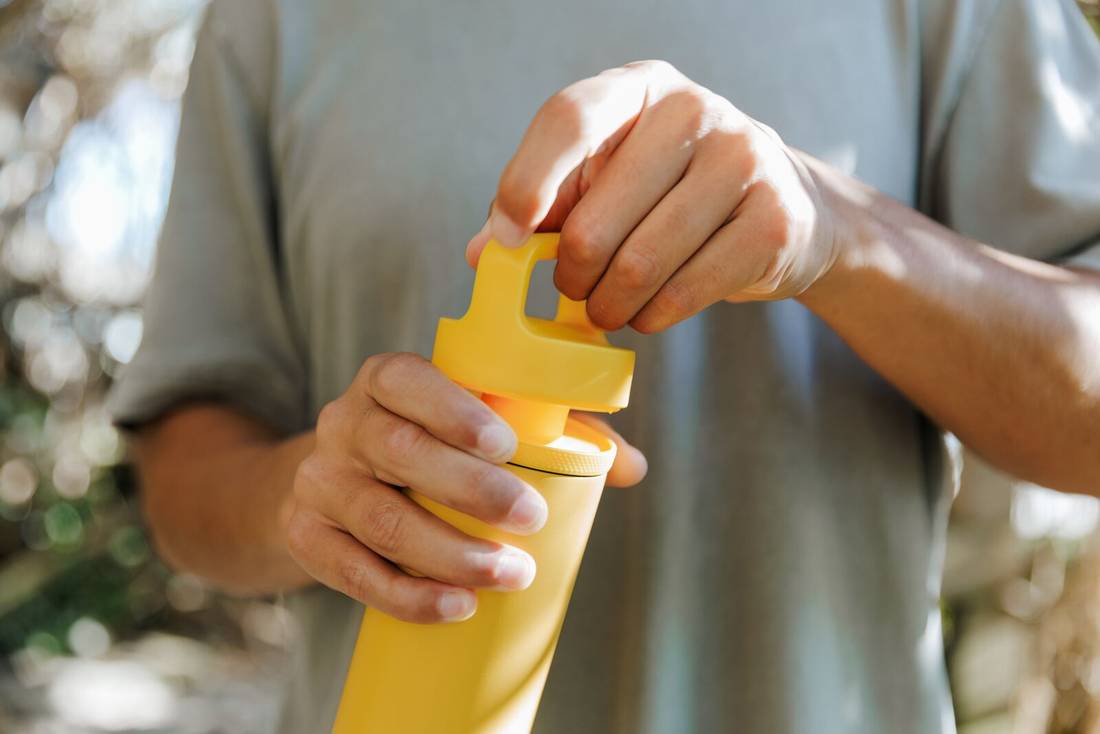 close up of person opening Spout Bottle showing the outer lid coming off 