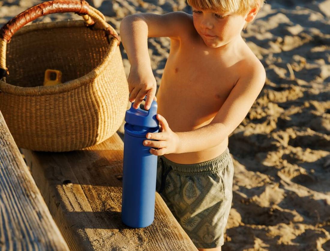 Little kid at the beach easily using spout bottle.