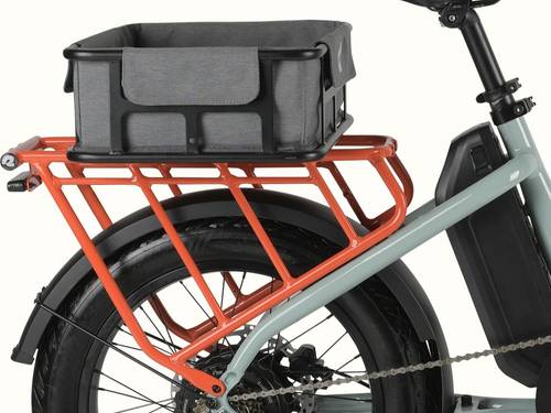 A closeup of the rear wheel and orange rear rack of an electric bike with a covered metal basket attached.