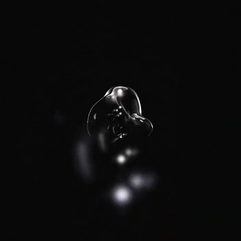 A shiny, abstract black shape in front of a dark background.