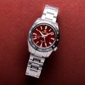 Grand Seiko SBGE305 Spring Drive GMT with red dial and black ceramic bezel.