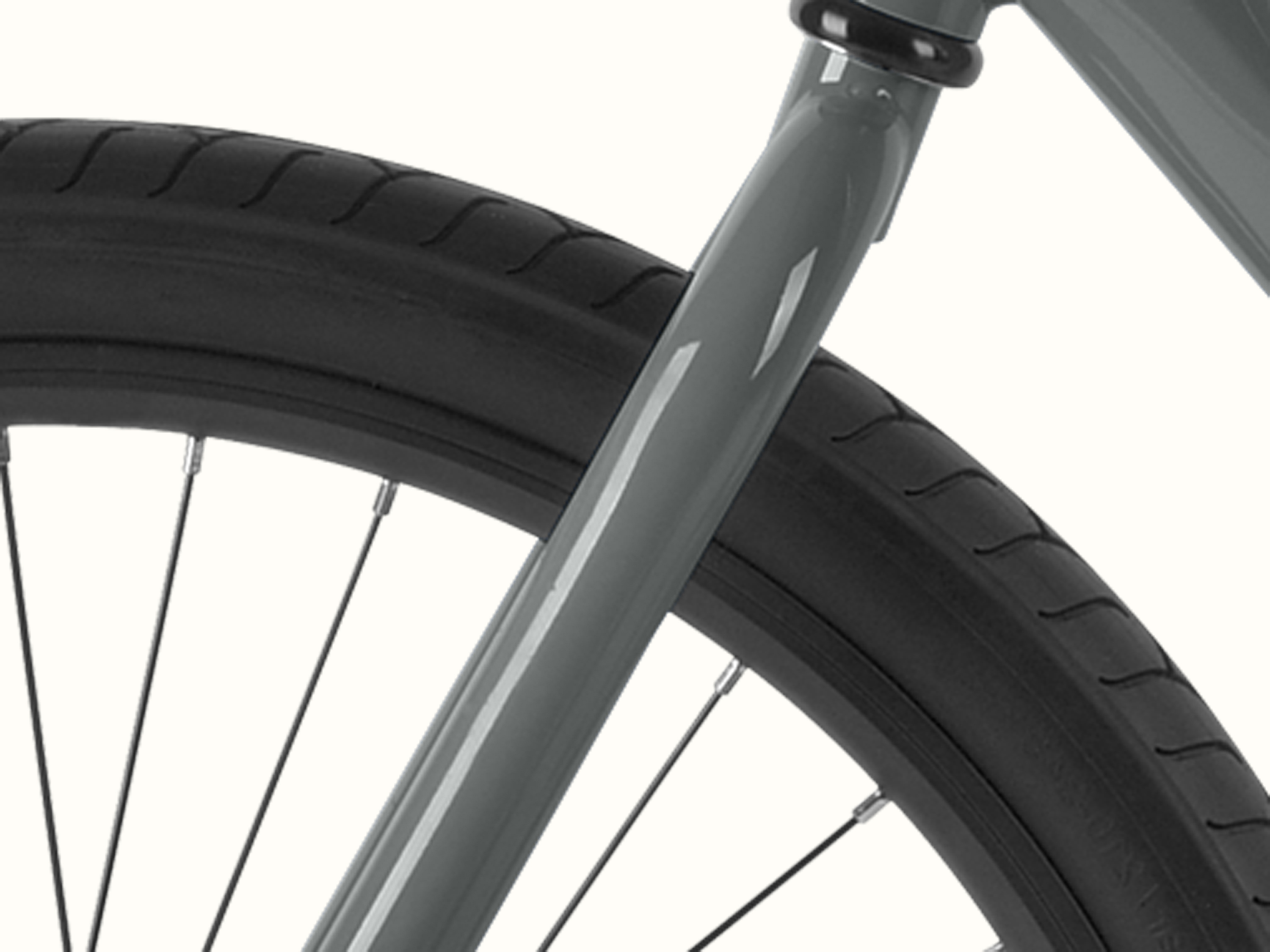Close-up of a black bicycle tire with tread pattern and a gray Montauk bike fork against a plain background.