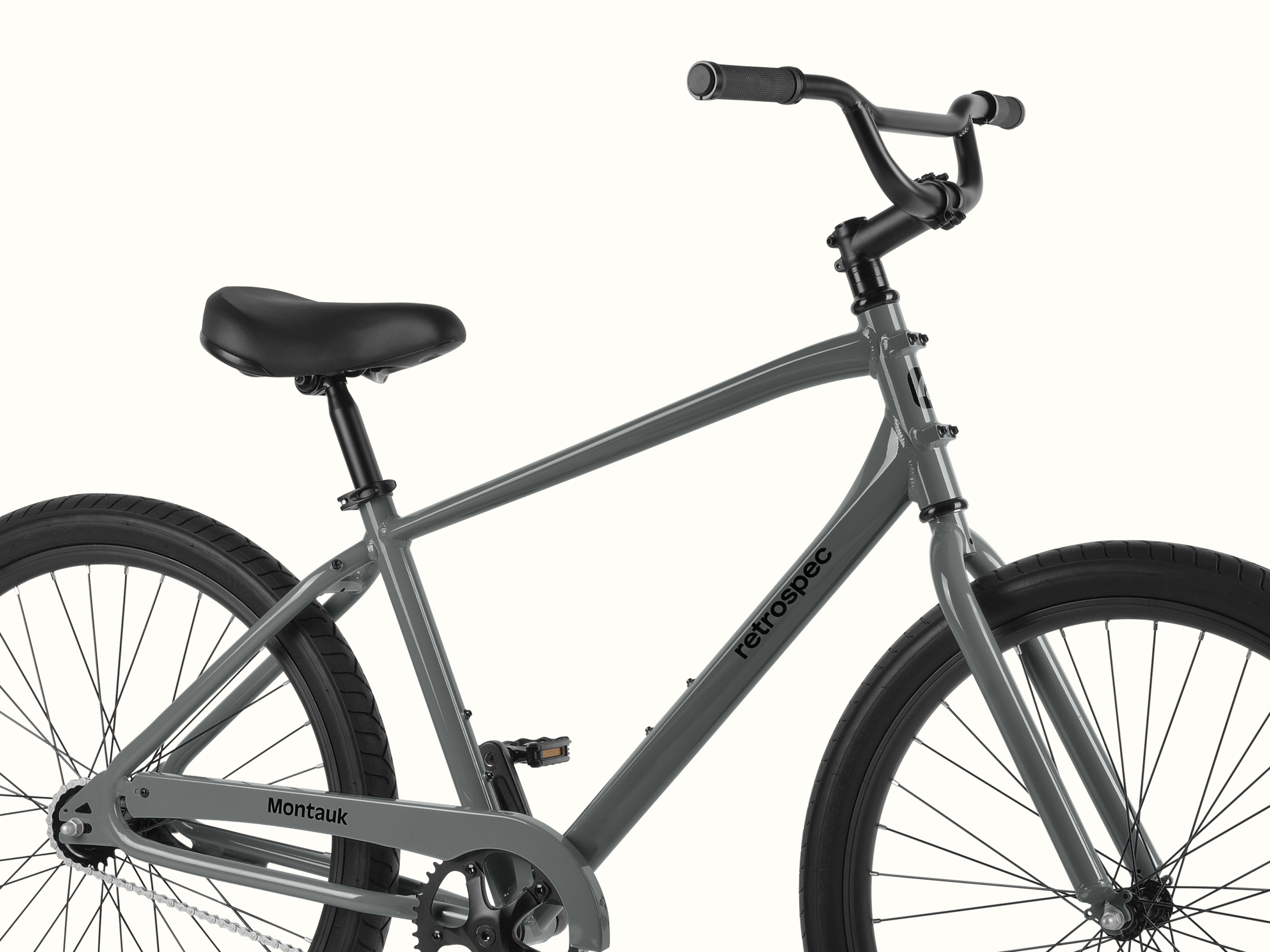Side view of a grey retrospec Montauk bicycle with black seat, handlebars, and tires on a white background.